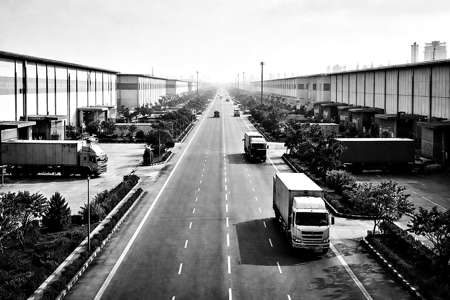 Warehouses and trucks along a logistics corridor